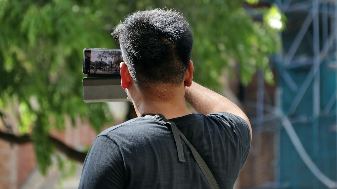 Camera operator filming a news presenter on set with a broadcast camera
