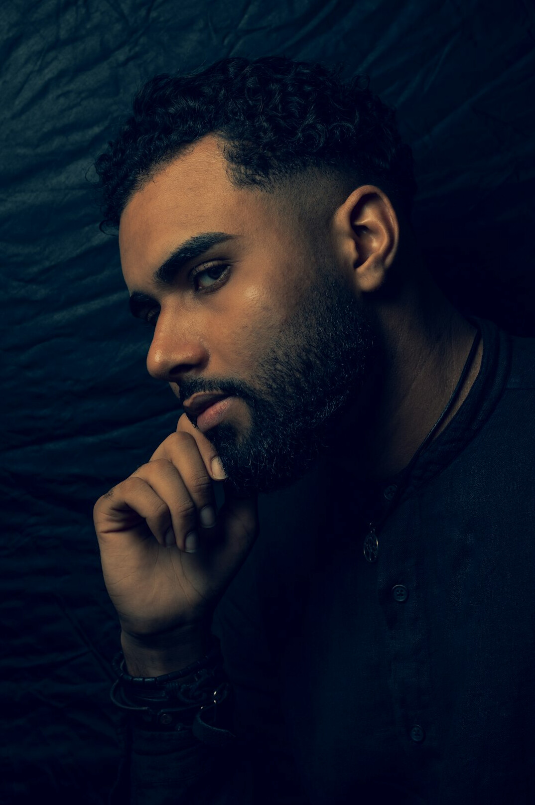 Studio portrait of a Black man with a short beard wearing a dark jacket